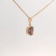 close-up of rose gold pendant with purple gemstone