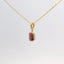gold pendant with an emerald-cut red stone, angled view