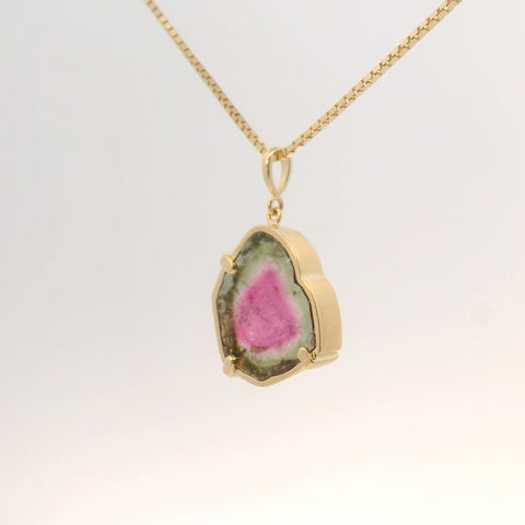 gold pendant showcasing pink and green tourmaline stone, angled view