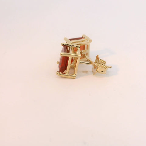 Gold tone earrings with red gemstones, close-up view.